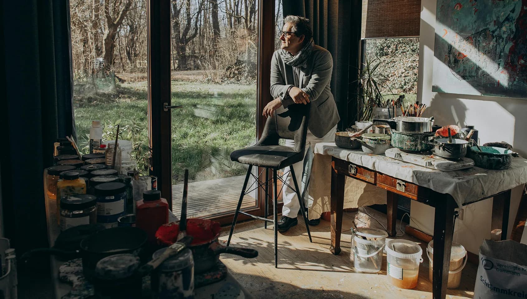 Artist in a sunlit studio looking outdoors