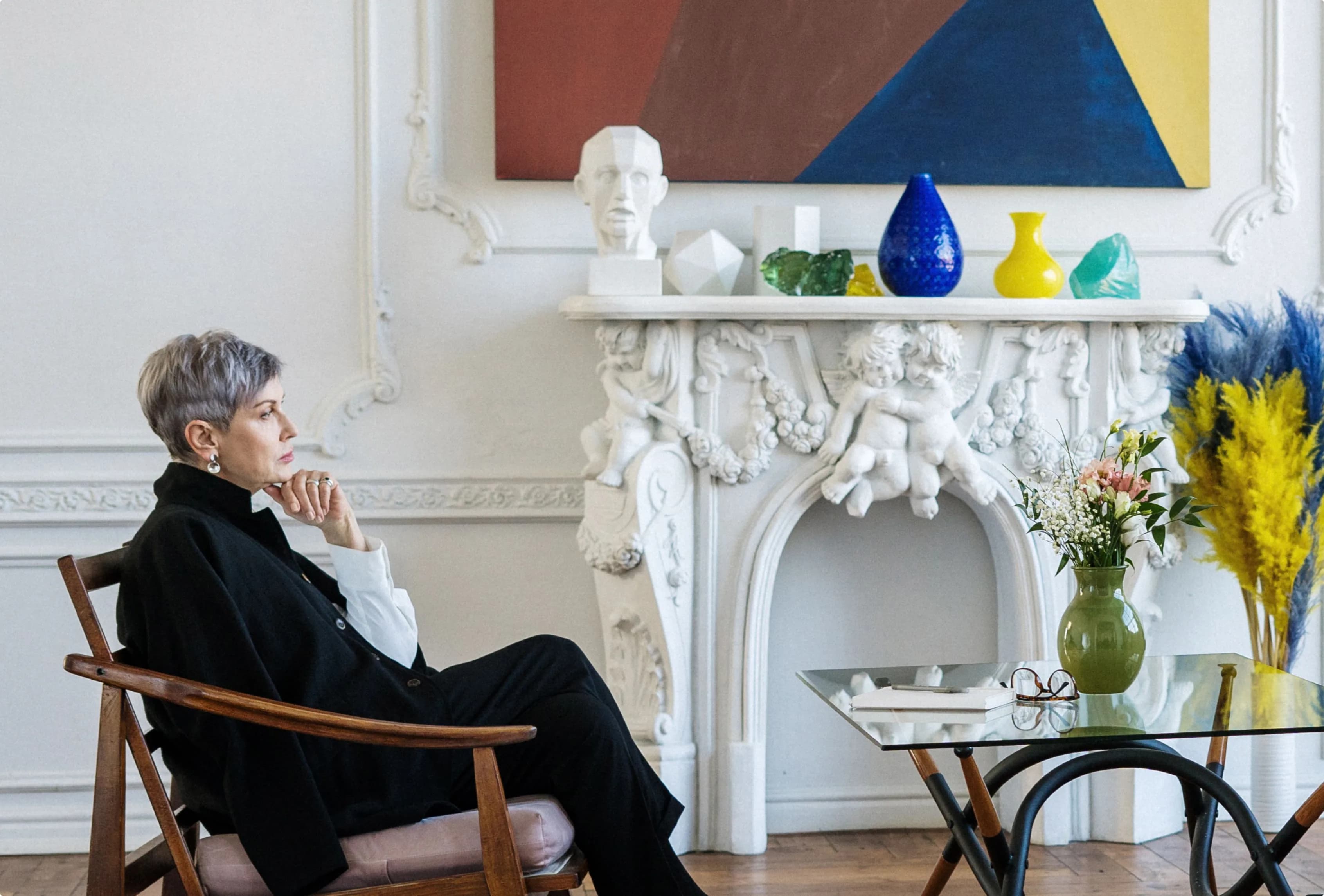 Gallerist seated beside a fireplace in a gallery