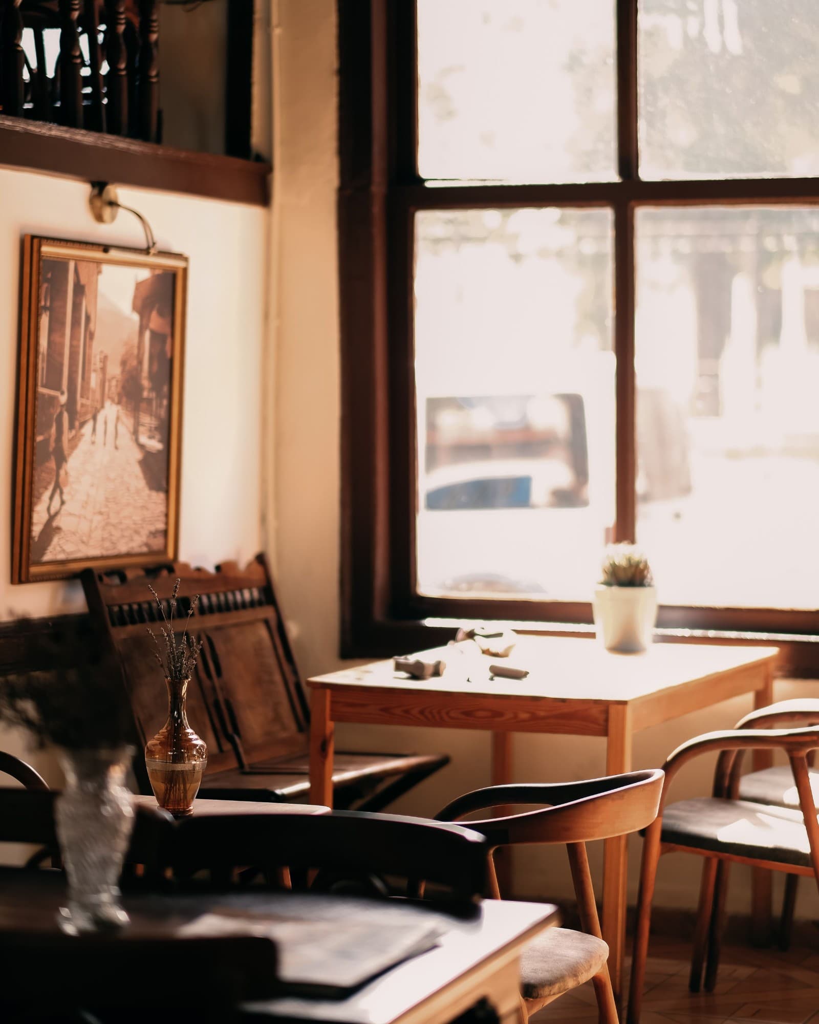 Sunlit café corner with a framed photograph and wooden chairs